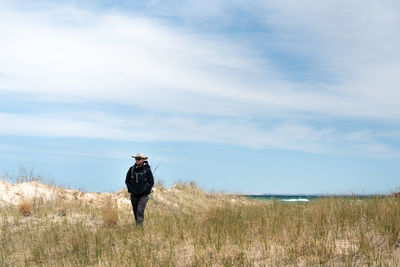 Man walking on field against sky