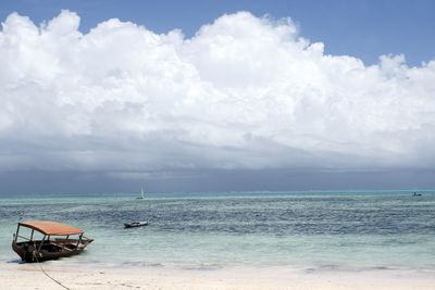 Boats in sea against cloudy sky