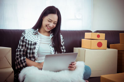 Young woman using phone while sitting on sofa at home