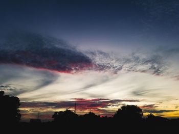 Low angle view of silhouette trees against dramatic sky