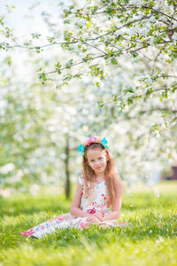 Portrait of cute girl sitting on grass at park