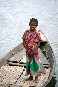 Portrait of boy standing on pier over lake