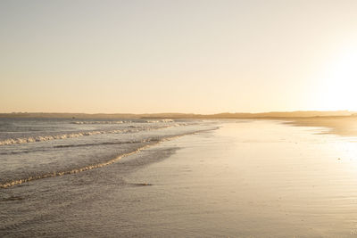 Scenic view of beach against clear sky during sunset