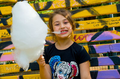 Portrait of girl eating cotton candy while standing outdoors