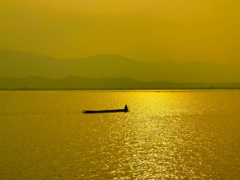 Silhouette people on boat in sea against sky during sunset