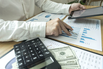 Midsection of man with digital tablet analyzing chart on table