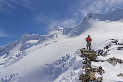 Man skiing on snow covered mountain against sky