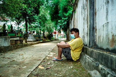 Side view of young man sitting on plants