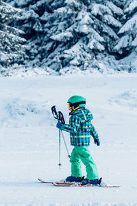 Full length of boy skiing against snow covered trees