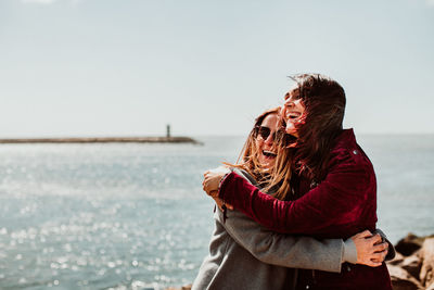 Young couple in sea against sky