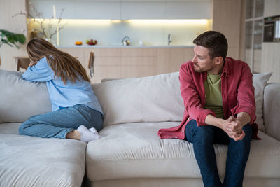 Young woman using mobile phone while sitting on bed at home