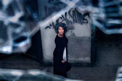 High angle portrait of woman seen through broken glass in abandoned building