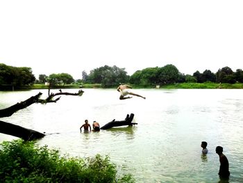 People swimming in lake against clear sky