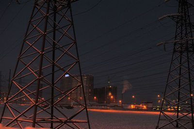 Low angle view of electricity pylon against sky during sunset