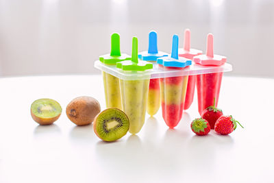 A plastic mold with multi-colored homemade kiwi and strawberry ice cream stands on a white table