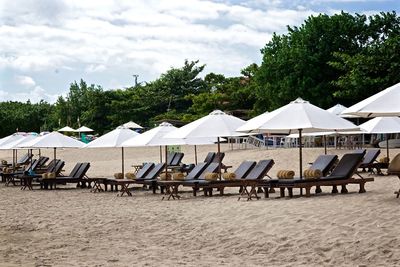 Chairs and tables on beach against sky