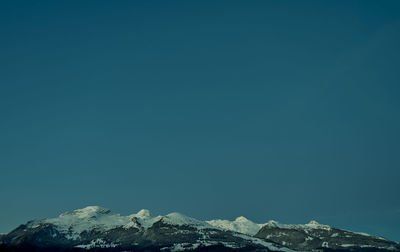 Scenic view of snowcapped mountains against clear blue sky