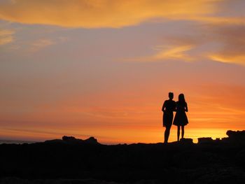 Silhouette of women standing against sky during sunset