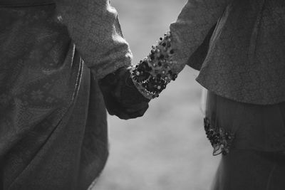 Close-up of wedding couple holding hands outdoors