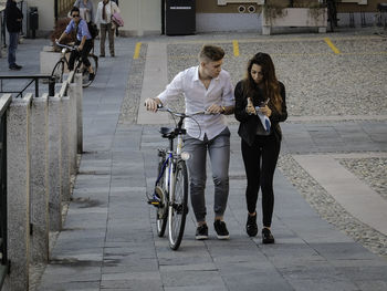 Woman with bicycle on sidewalk