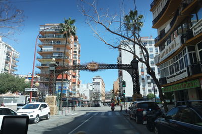 Cars on street in city against clear sky