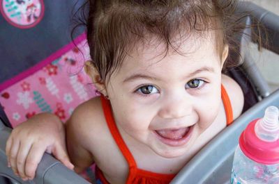 Close-up portrait of cute smiling baby girl while sitting in baby carriage