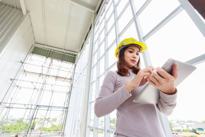 Low angle view of young woman using mobile phone