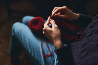 Female hands knitting with red yarn. creative hobby