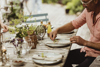 Mature man arranging plate on dining table