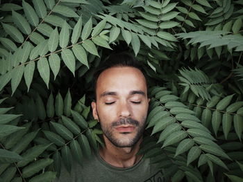 Portrait of young man with green leaves