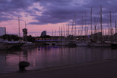 Sailboats moored at harbor against sky during sunset