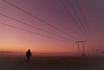 Silhouette woman standing on field against sky during sunset