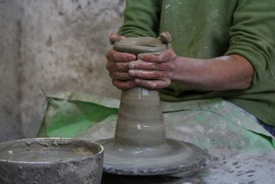 Midsection of male potter making pot at workshop