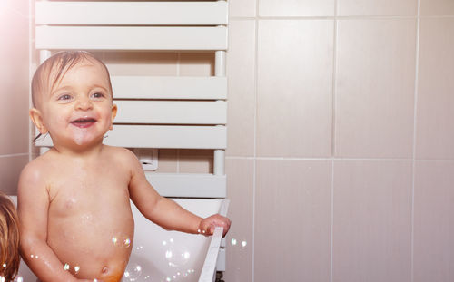 Portrait of cute boy standing against wall