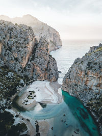 Rock formation by sea against sky