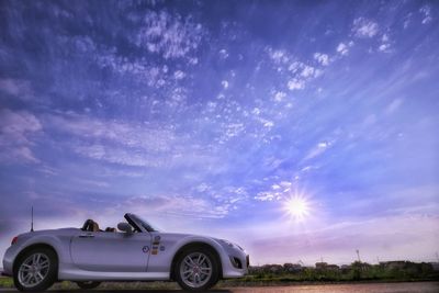 Vintage car on field against blue sky