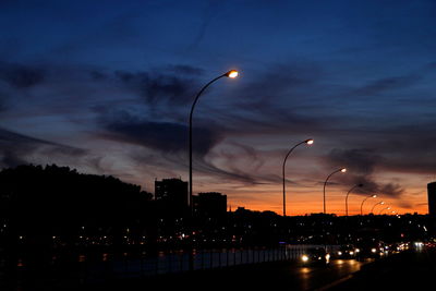 Illuminated street lights against sky at night