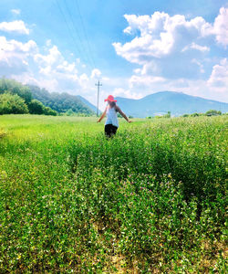 Woman standing by plants against sky