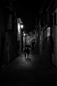 Rear view of man walking in illuminated building at night