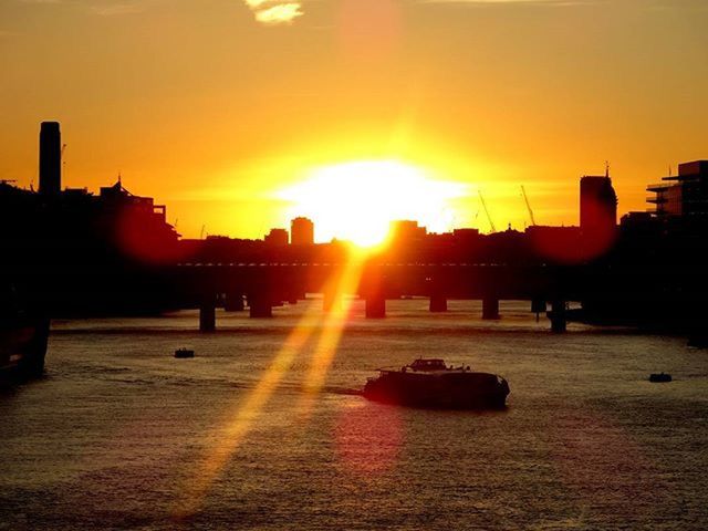 sunset, sun, orange color, silhouette, built structure, architecture, sunlight, transportation, building exterior, sunbeam, lens flare, water, mode of transport, sky, nautical vessel, city, reflection, river, beauty in nature