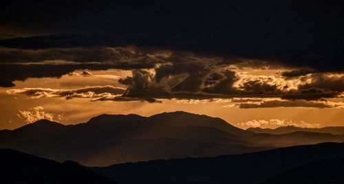 Scenic view of silhouette mountains against dramatic sky