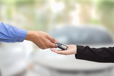 Cropped hand of male salesman giving car keys to female customer