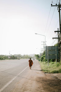 Rear view of woman walking on road against sky