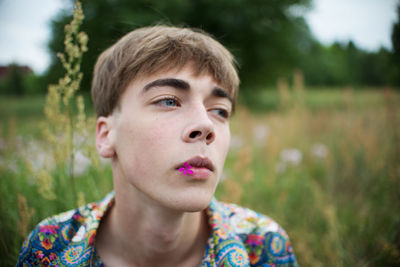 Close-up of young man looking away against plants