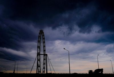 Low angle view of crane against cloudy sky