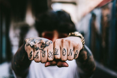 Close-up of hipster showing tattooed hands in city