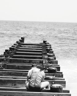 Rear view of man sitting on staircase against sea