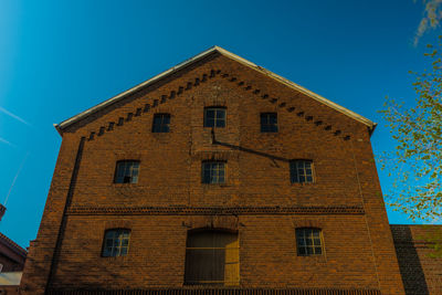 Low angle view of old building against clear blue sky