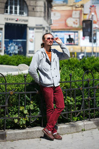 Man wearing sunglasses while standing against railing and plants 