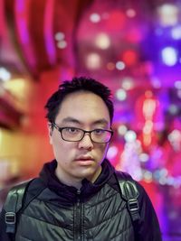 Portrait of young man standing against illuminated lights